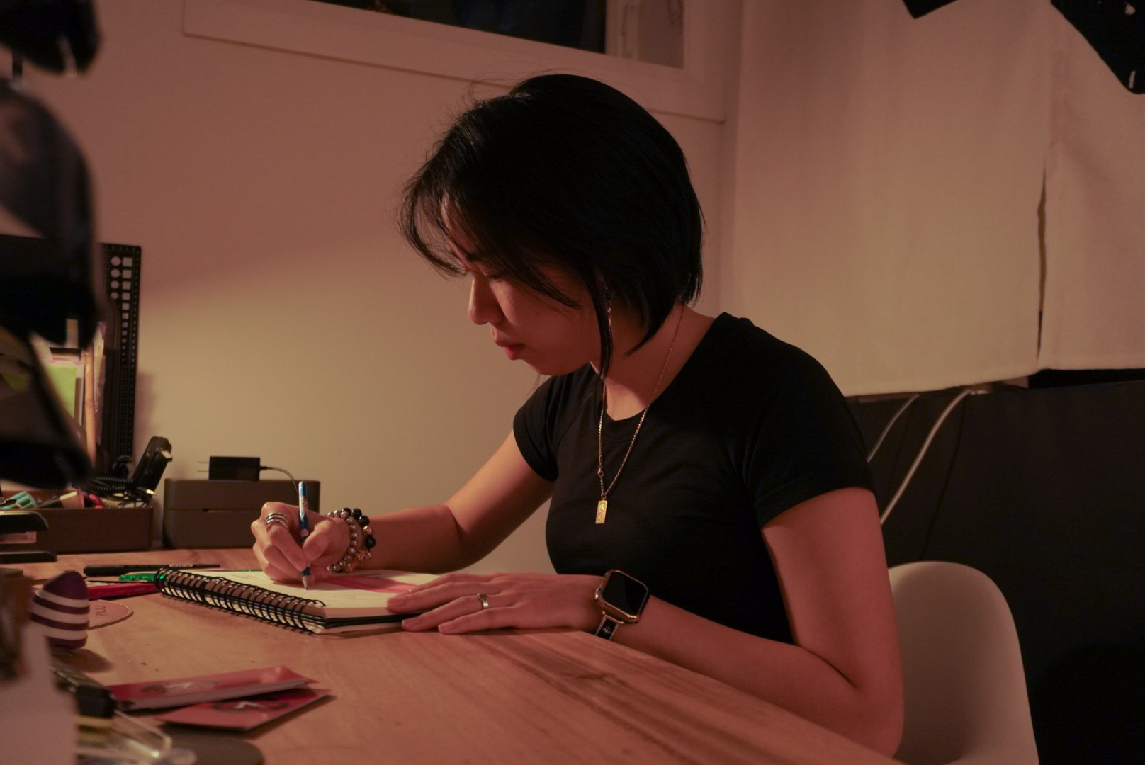 Kyra Tang writing in a notebook at her workspace