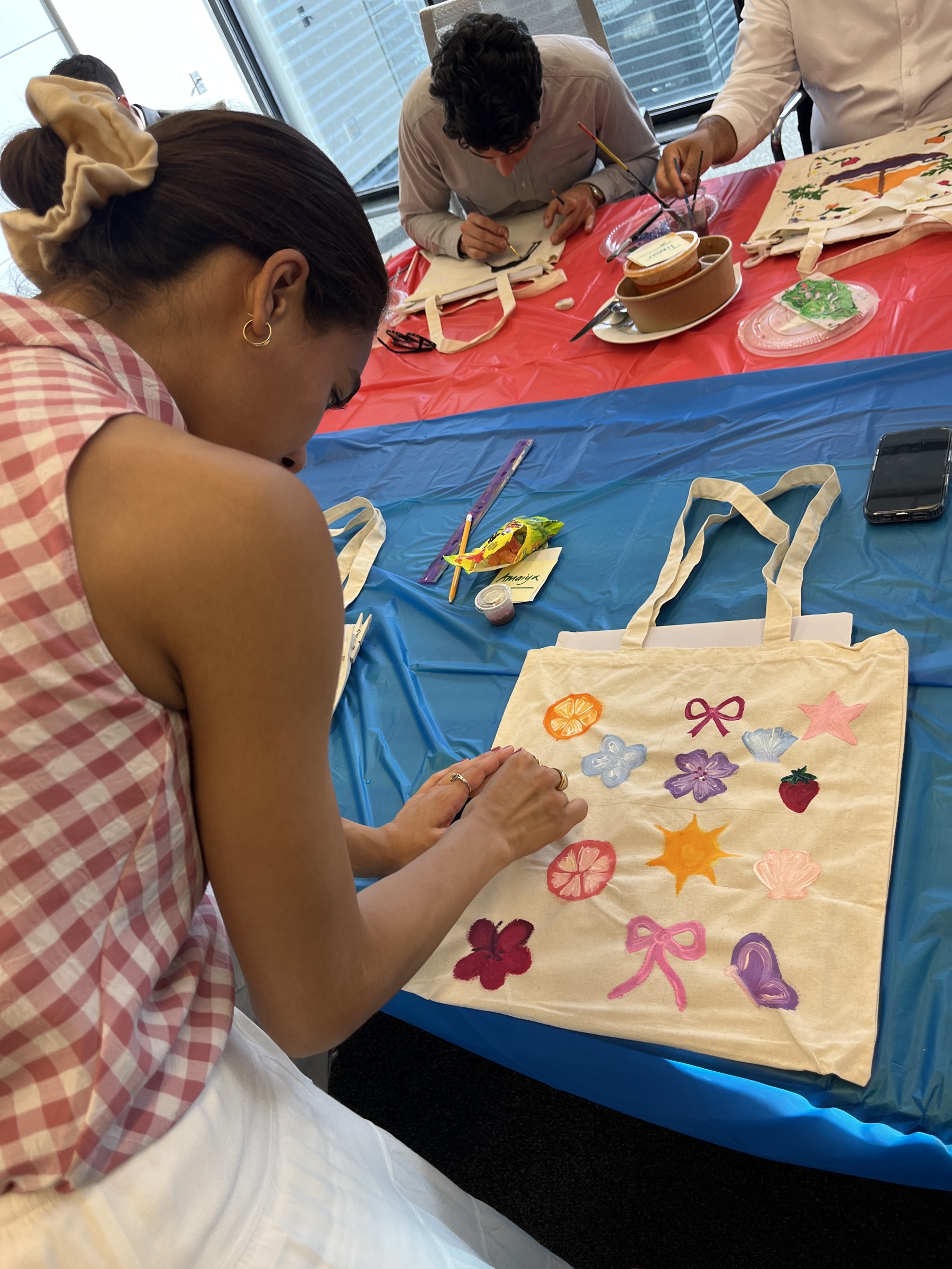Participants painting designs on tote bags