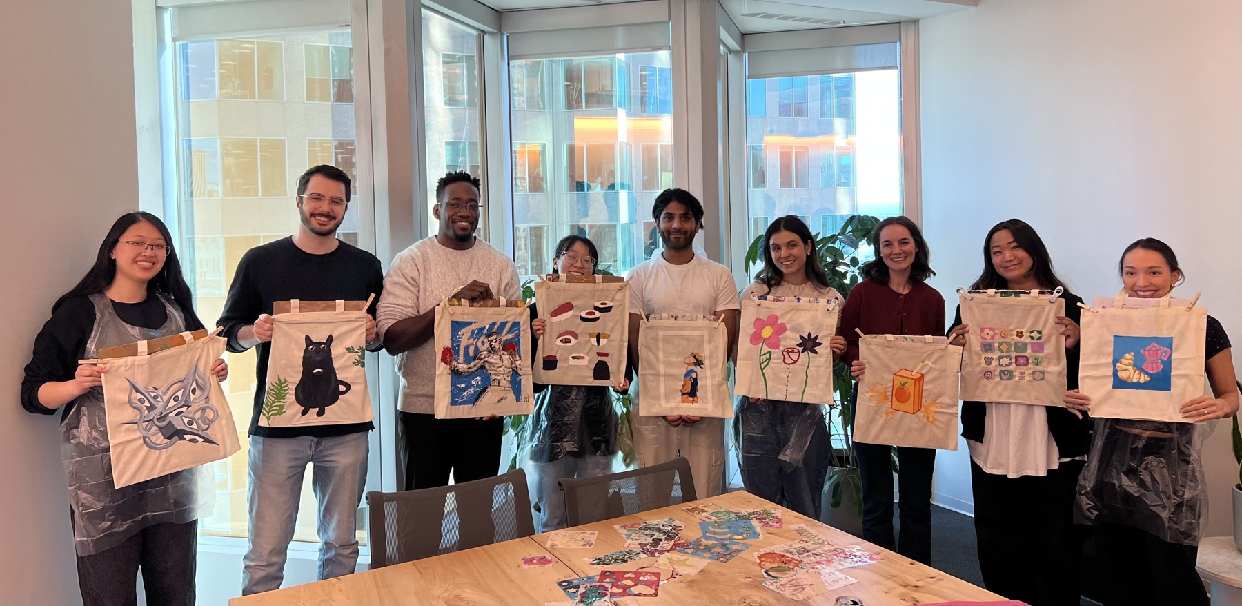 Workshop participants displaying their painted tote bags