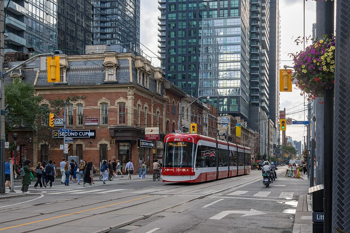 A red Toronto streetcar beside downtown office buildings