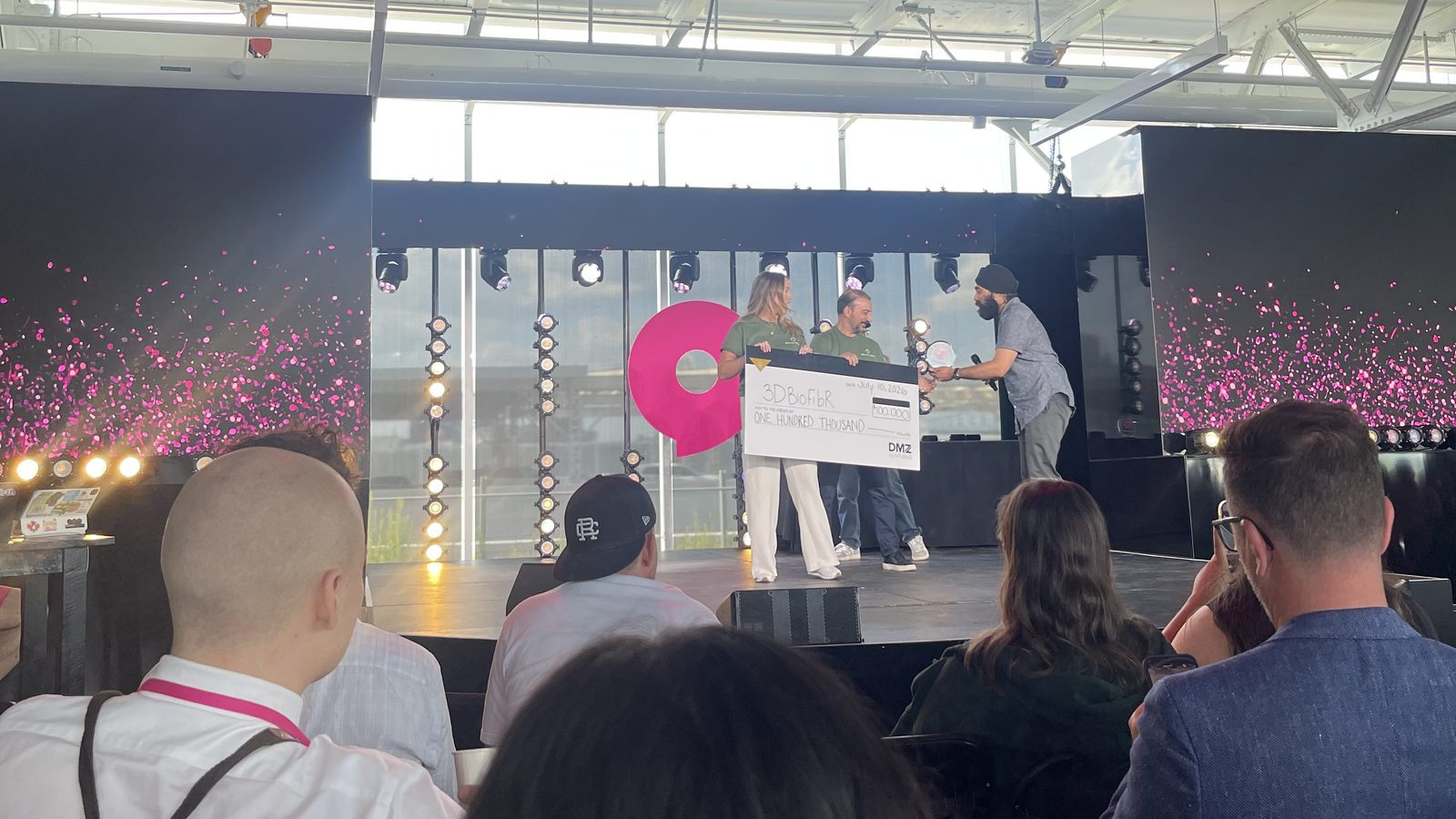 3DBioFibR founders on stage at Startupfest Montréal holding a $100,000 cheque as confetti fills the screens behind them